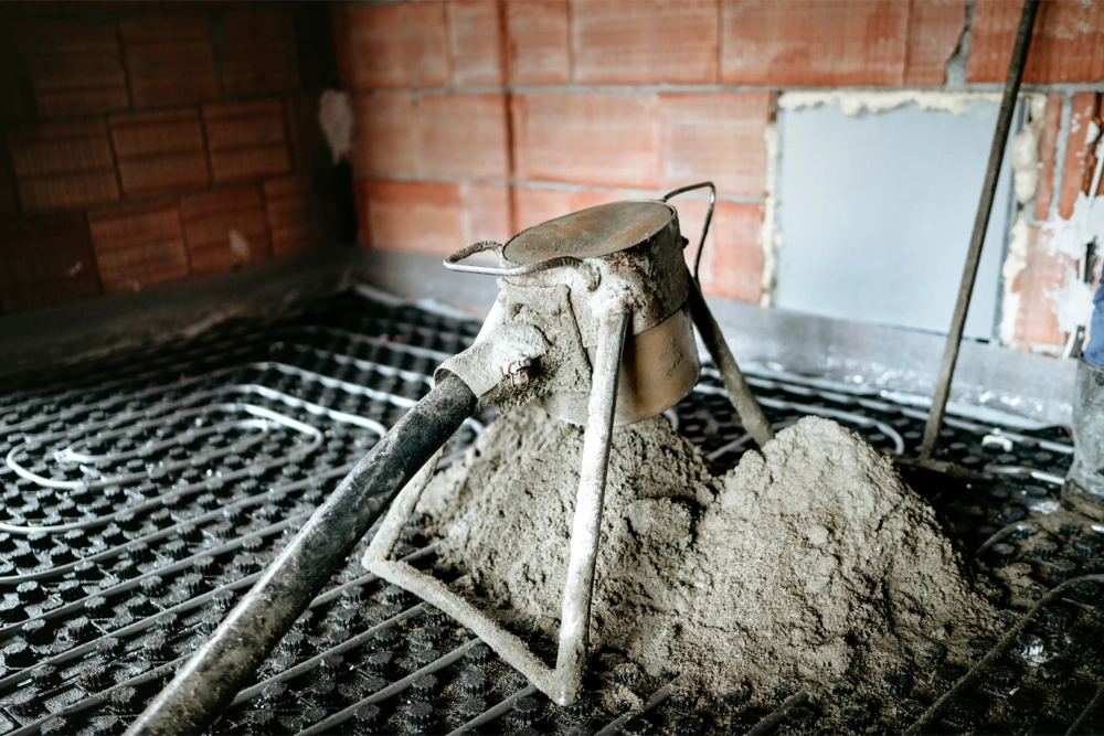 Obróbka betonu - pompowanie zaprawy na instalacji ogrzewania podłogowego z widocznym wężem i dyszą